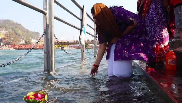 young girl devotee offering flower pot to holy river ganges at morning from flat angle