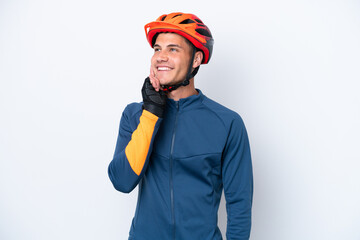 Young cyclist caucasian man isolated on white background thinking an idea while looking up