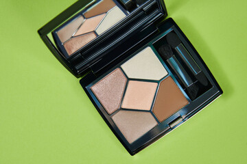 palette of warm gentle natural shades of eye shadow close-up on a green background