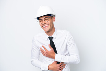 Young architect caucasian man with helmet and holding blueprints isolated on white background smiling a lot