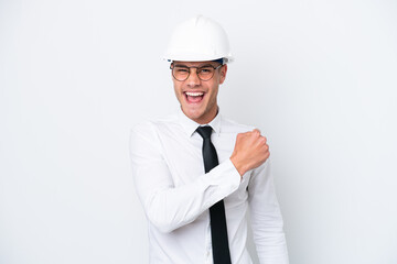Young architect caucasian man with helmet and holding blueprints isolated on white background celebrating a victory