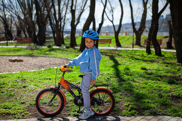Fototapeta premium Happy kid boy of 5 years having fun in spring park with a bicycle on beautiful fall day. 