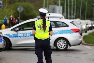 Policjantka ruchu drogowego kieruje ruchem ma skrzyżowaniu dróg w mieście.  - obrazy, fototapety, plakaty