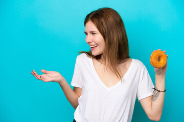 Young English woman holding a donut over isolated blue background with surprise facial expression