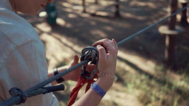 A woman going to drive on a zip line and checking up the safety rope