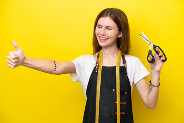 Young seamstress English woman isolated on yellow background giving a thumbs up gesture