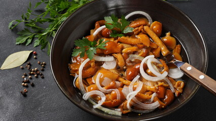 Marinated wild honey fungus Armillaria mellea mushrooms with spices and onions in the bowl.