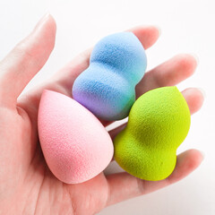 Woman's hand holding a clean make up sponges on white background.