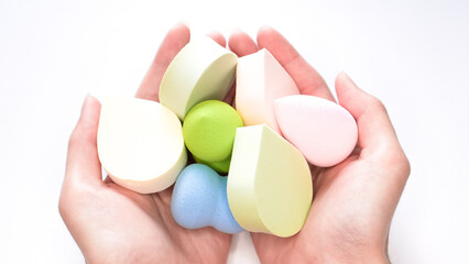 Woman's hands holding a clean make up sponges on white background.