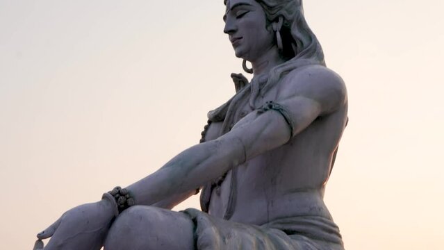 hindu god lord shiva statue in meditation posture with flat sky at evening from low angle