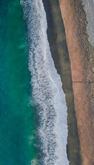 Aerial view on the beach with aquamarine sea  and waves breaking on the beach