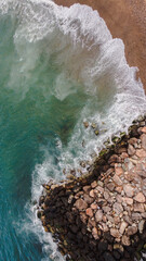 Aerial view on the beach with aquamarine sea, rocks and waves breaking on the beach