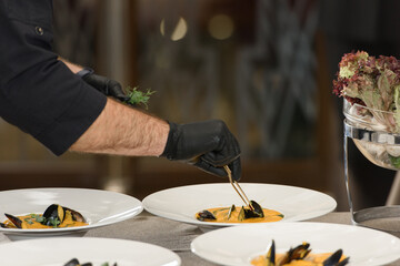 chef prepares carrot cream soup with seafood in a restaurant
