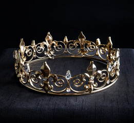 close up of a g beautiful real golden crown, isolated on dark black studio background.
