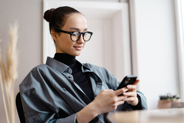 Uses phone manager freelancer Woman wearing glasses work office