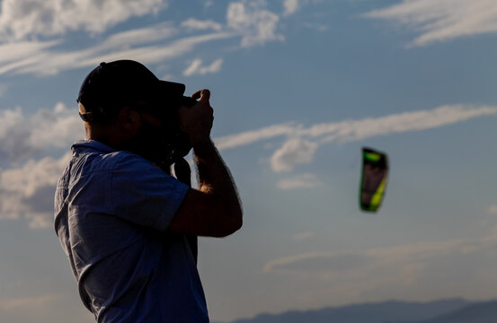 A professional photographer with a cap takes pictures of kite surfing