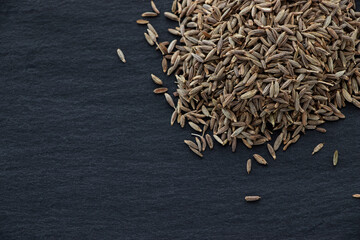 Сumin seeds on a dark stone background