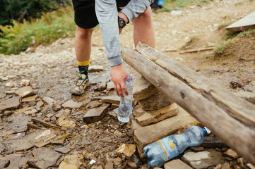 Male hiker in the mountains collects water from a bottle from a spring, close up photo