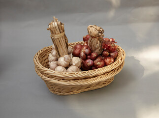 Shallots and Garlic Bundled in a basket lay on a gray background