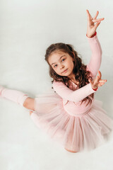 Little ballerina dancer in a pink tutu academy student posing on white background 