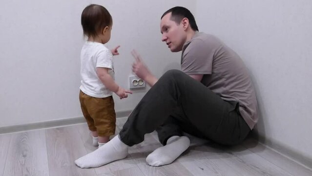 the father installs plugs on sockets for the safety of the child