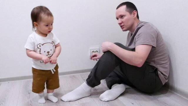 Dad explains to the child that it is dangerous to touch the sockets