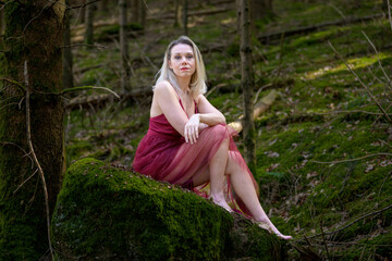 Confident woman sitting on moss covered rock.