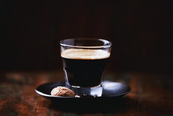 Coffee in glass cup on dark wooden background. Close up.