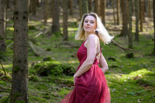 Pretty blond woman turning around against trees in woods.