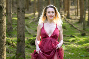 Attractive blond woman in magenta dress at forest.