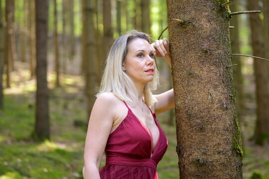 Thoughtful woman in sensuous dress posing at forest.