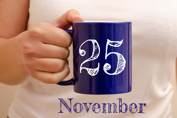 The inscription on the blue cup 25 november. Cup in female hand, business concept