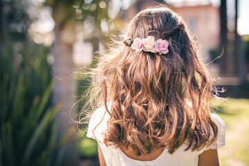 Flower hair of a first communion girl with her back turned in a park