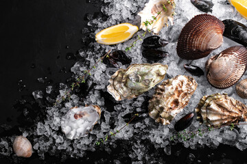 Raw oysters and mussels on ice on black slate. Fresh Clams in whole shells for cooking with seasonings on the table