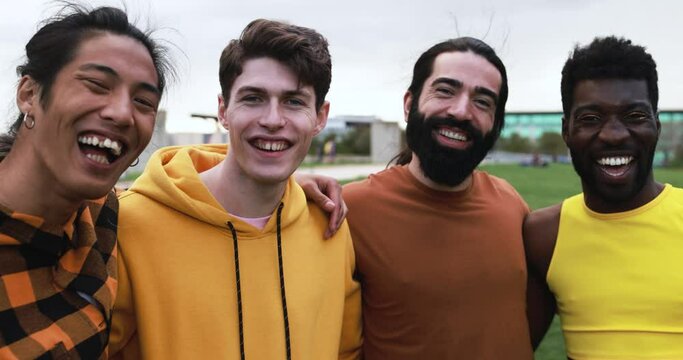 Young diverse men having fun laughing together at city park