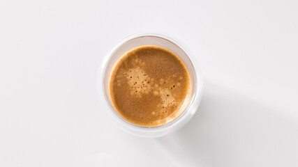Freshly brewed coffee in a glass cup on a white background, top view, central composition