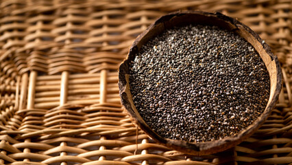 Chia seeds in a coconut bowl on a wicker wooden background
