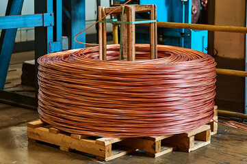 Large bobbin of orange copper wire in light warehouse