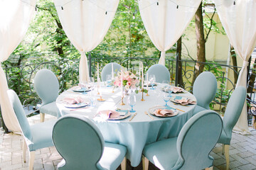 Wedding decor in blue. Banquet tables decorated bouquet with peonies on the tables are pink plates, glasses and candles