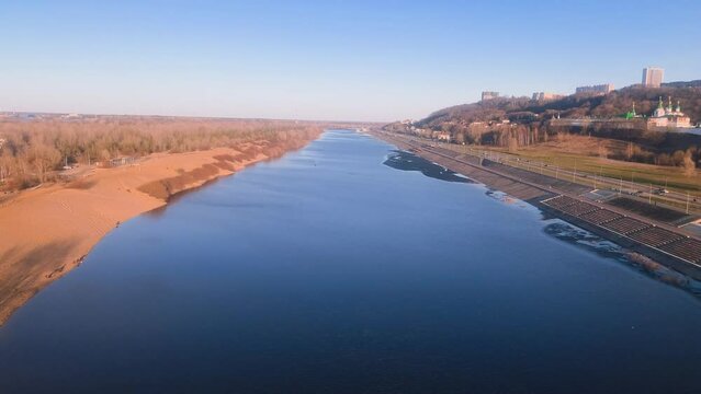 Volga, Nizhny Novgorod. In the foreground you can see the blue Ceta river, on the left a sandy beach with growing trees and shrubs, on the right a road with passing cars, top view. High quality 4k