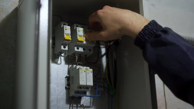 Electrician switches on the breakers in a fuse box, Master powers on switches in the technical room. Man turns on electrical appliances in a district heating substation.