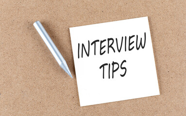 INTERVIEW TIPS text on sticky note on a cork board with pencil ,