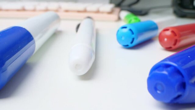 detailed extreme close-up of multicolored markers and a pink computer keyboard on a white table