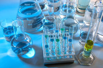 Laboratory equipment such as beaker, flask, cylinders and test tubes under a bluish light
