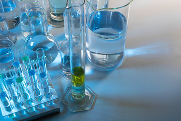 Laboratory equipment such as beaker, flask, cylinders and test tubes under a bluish light