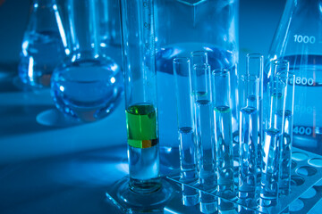 Laboratory equipment such as beaker, flask, cylinders and test tubes under a bluish light