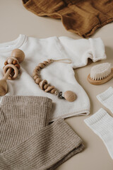 Stylish elegant newborn baby clothes and accessories on neutral pastel beige background. Sweater,...