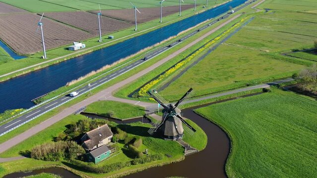Aerial view from drone on colorful tulip fields, windmills, wind turbines, water canals and agricultural work in Netherlands countryside. High quality 4k footage