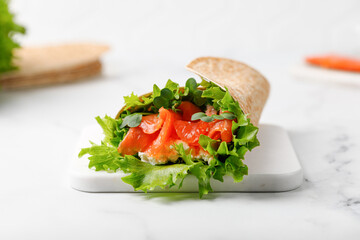 Wrap sandwich, roll with salmon and lettuce leaves. Tortilla wraps with salmon and micro greens.