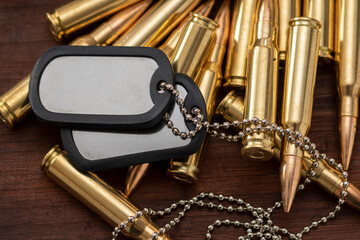 Army identification tokens lie on scattered yellow machine gun cartridges, selective focusing....